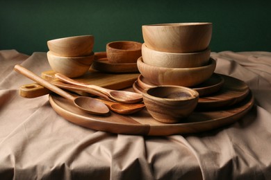 Set of wooden dishware and utensils on table against green background