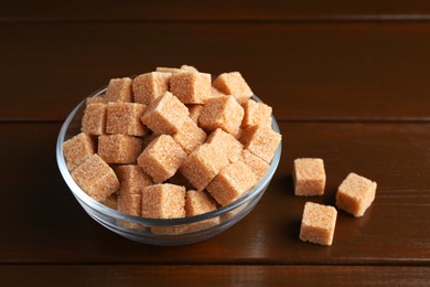 Photo of Brown sugar cubes in glass bowl on wooden table