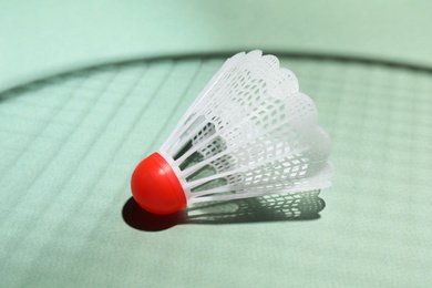 Photo of Plastic shuttlecock and shadow of racquet on light background, closeup. Badminton equipment