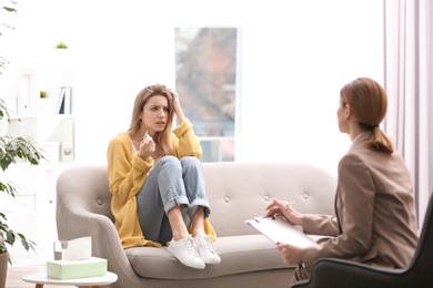 Psychotherapist working with young woman in light office