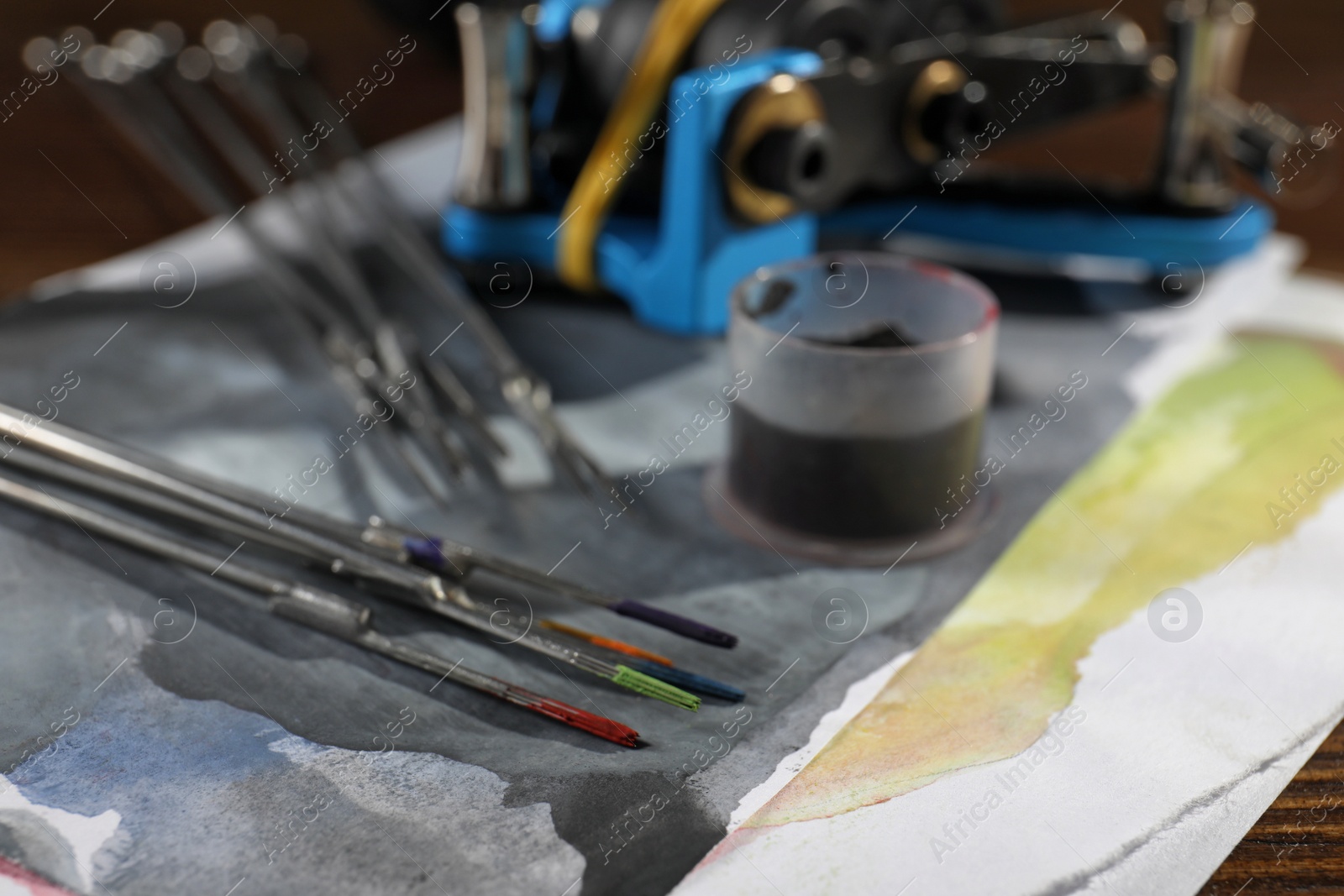 Photo of Tattoo needles with ink on painted paper, closeup