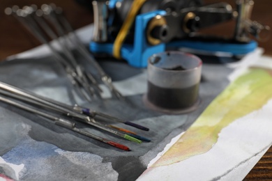 Tattoo needles with ink on painted paper, closeup