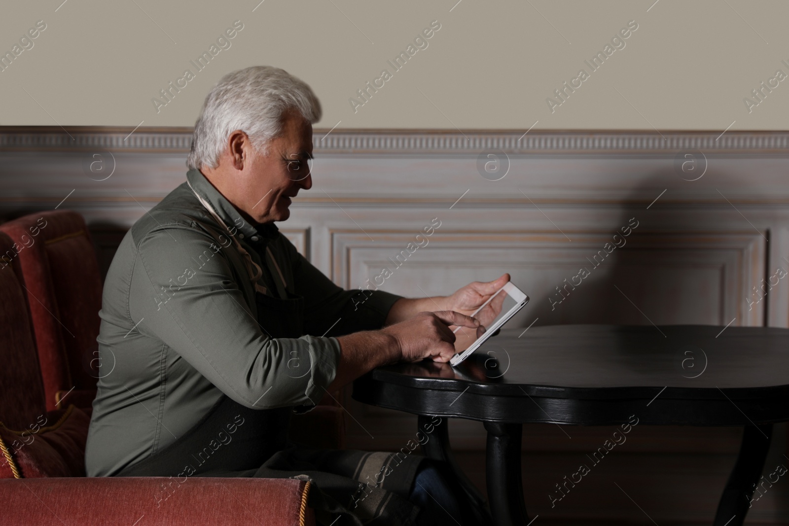 Photo of Senior business owner with tablet in his restaurant