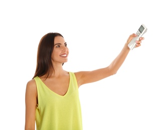 Young woman turning on air conditioner against white background