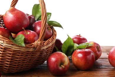 Ripe red apples and leaves on wooden table against white background