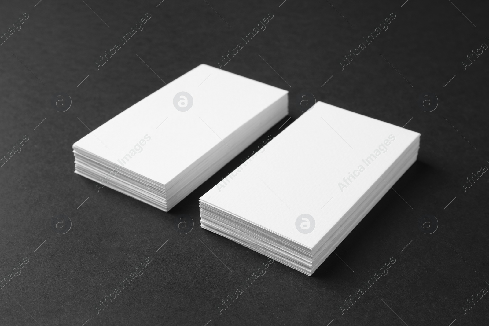 Photo of Stacks of blank business cards on black background. Mockup for design