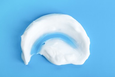 Photo of Body cream sample on light blue background, closeup. Cosmetic product