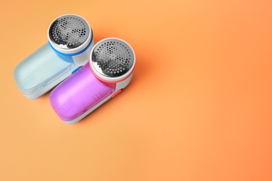 Modern fabric shavers on pale orange background, flat lay. Space for text