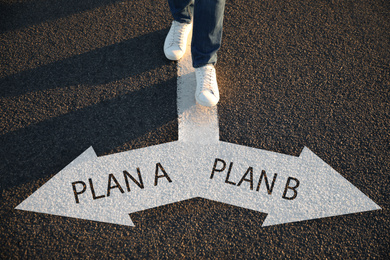 Choosing between Plan A and Plan B. Man near pointers on road, closeup view