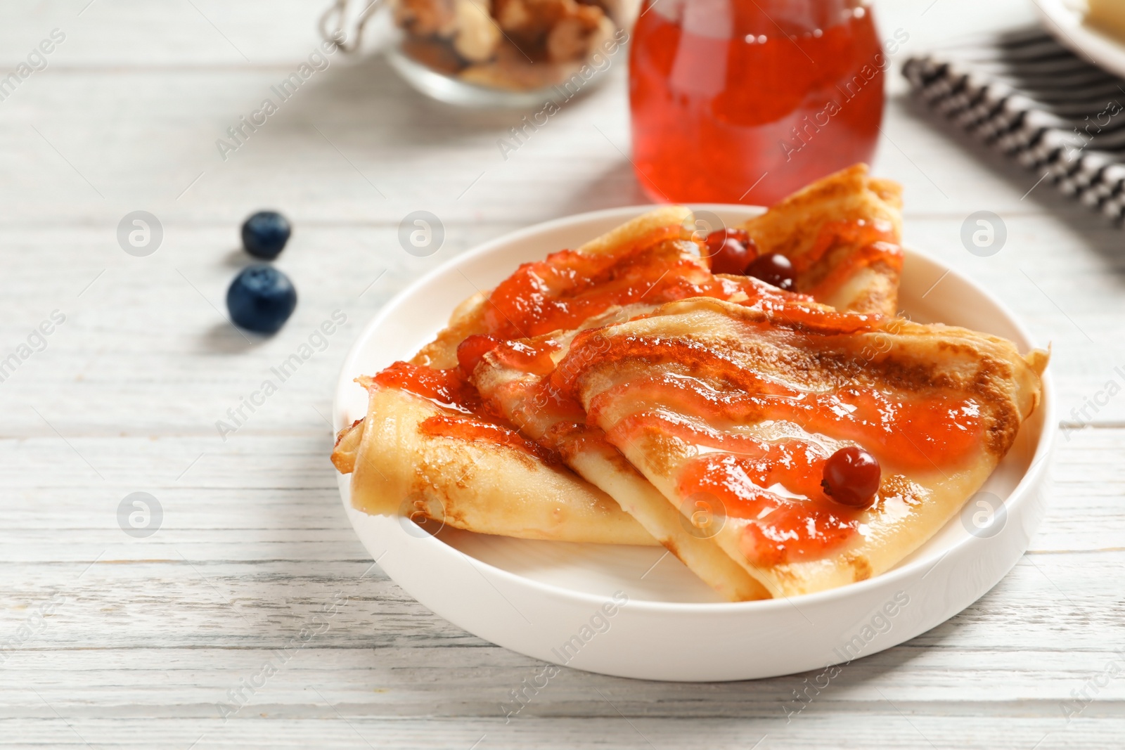 Photo of Thin pancakes served with syrup and berries on plate