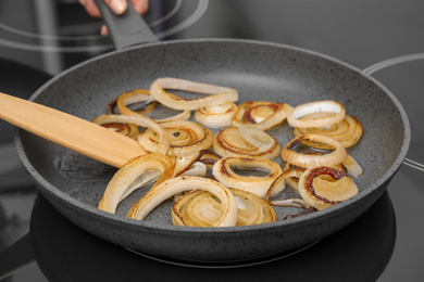 Photo of Cooking onion rings in frying pan, closeup