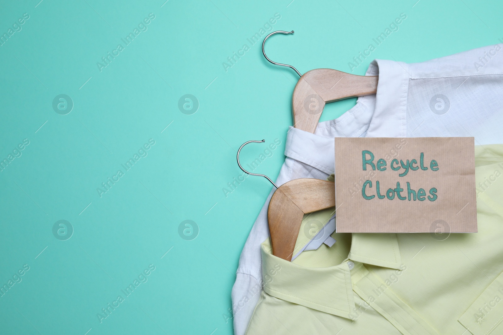 Photo of Recycling concept. Clothes and card with phrase on turquoise background, flat lay. Space for text