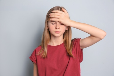 Photo of Teenage girl suffering from headache on grey background