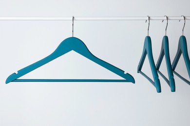 Photo of Blue clothes hangers on metal rail against light background