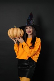 Beautiful woman wearing witch costume with pumpkin for Halloween party on black background