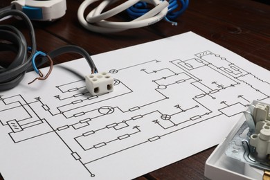 Wiring diagram, wires and disassembled light switch on wooden table, closeup