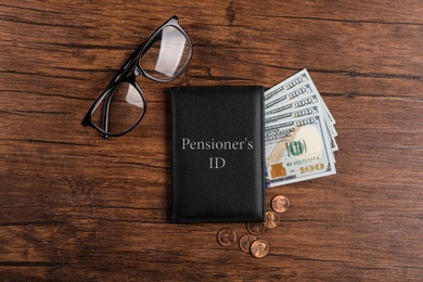 Photo of Pension certificate with American money and glasses on wooden table, flat lay