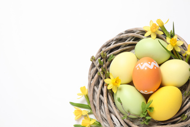 Photo of Colorful Easter eggs in decorative nest on white background, top view