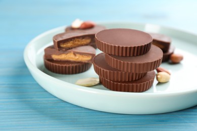 Photo of Delicious peanut butter cups on light blue wooden table, space for text