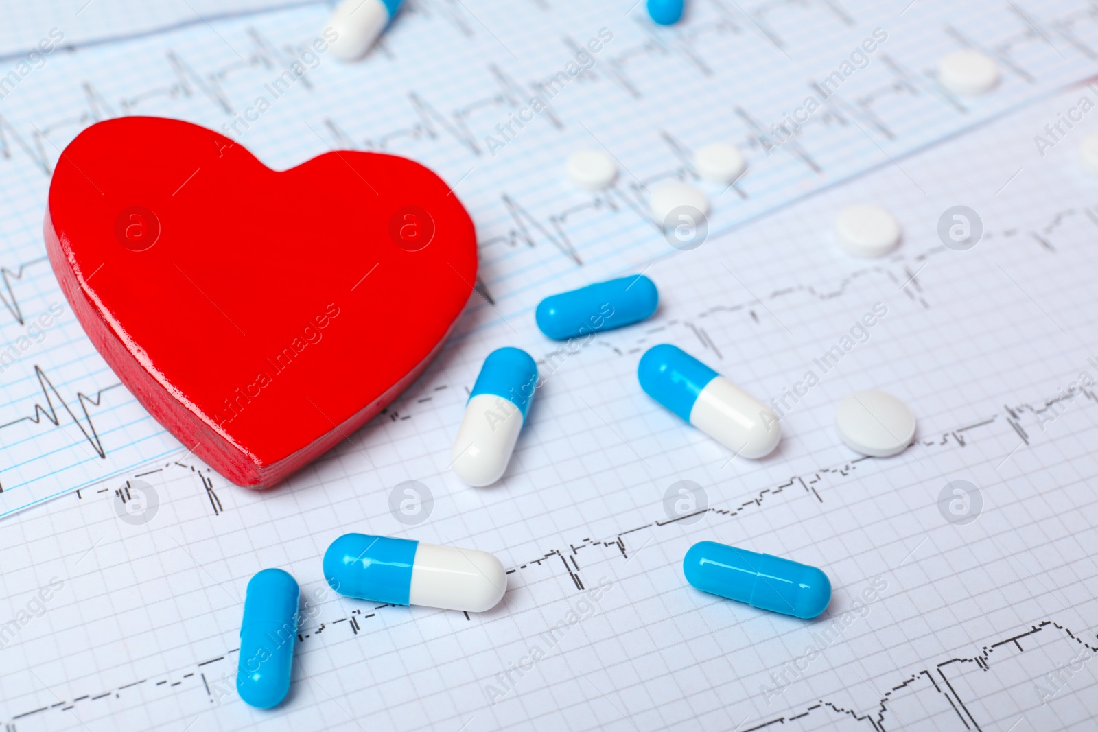 Photo of Red heart with pills on cardiogram. Cardiology concept