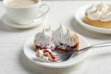 Photo of Tartlet with meringue served on white wooden table, closeup. Delicious dessert