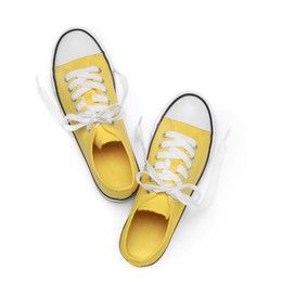 Photo of Pair of yellow classic old school sneakers isolated on white, top view