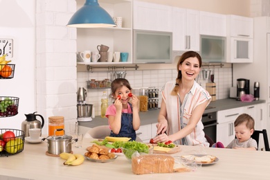 Photo of Housewife preparing dinner with her children on kitchen