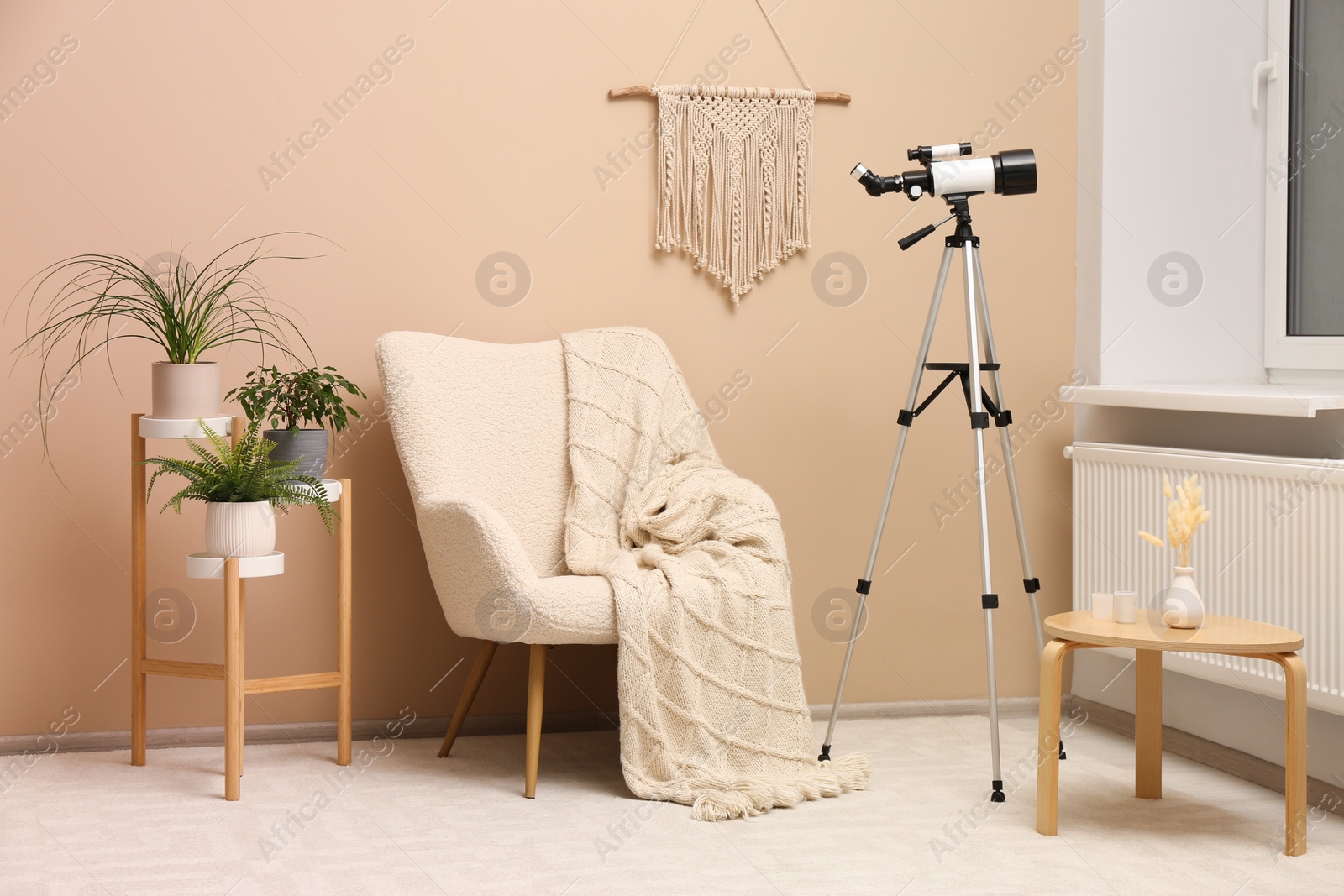 Photo of Tripod with modern telescope in stylish room