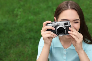 Photo of Young woman with camera taking photo outdoors, space for text. Interesting hobby