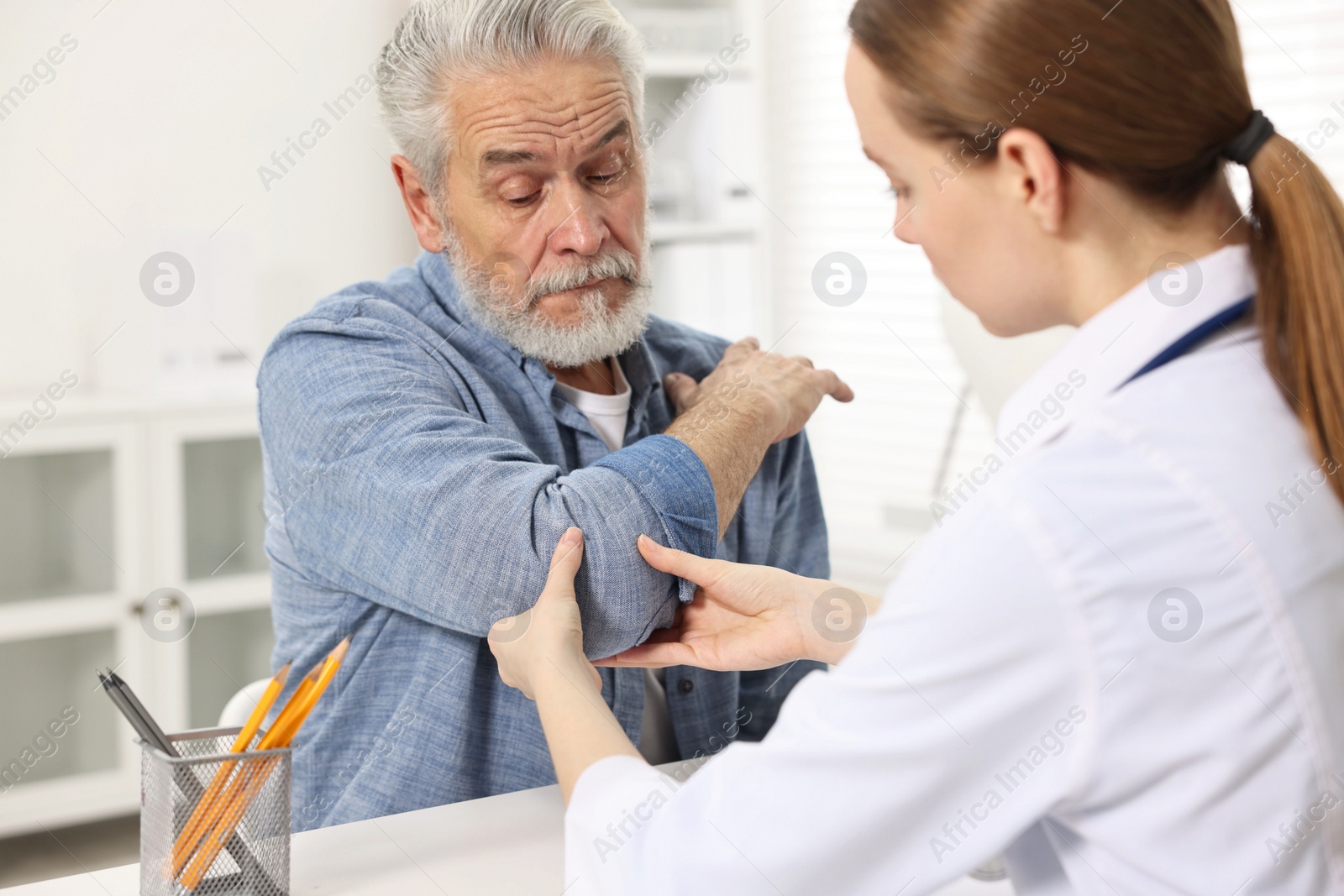 Photo of Arthritis symptoms. Doctor examining patient's elbow in hospital