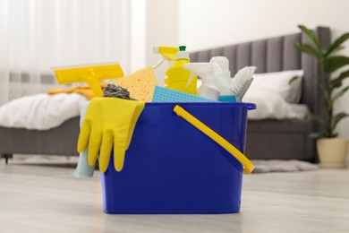 Photo of Different cleaning supplies in bucket on floor at home