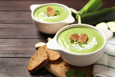 Photo of Tasty homemade zucchini cream soup served on wooden table