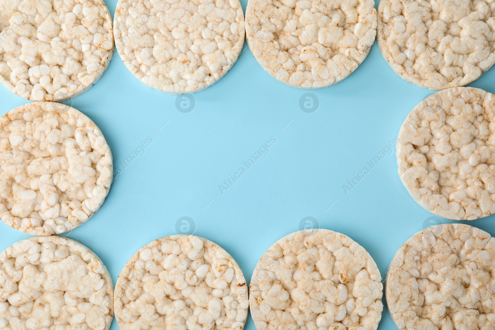 Photo of Frame made of puffed rice cakes on light blue background, flat lay. Space for text