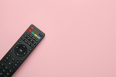 Remote control on pink background, top view. Space for text