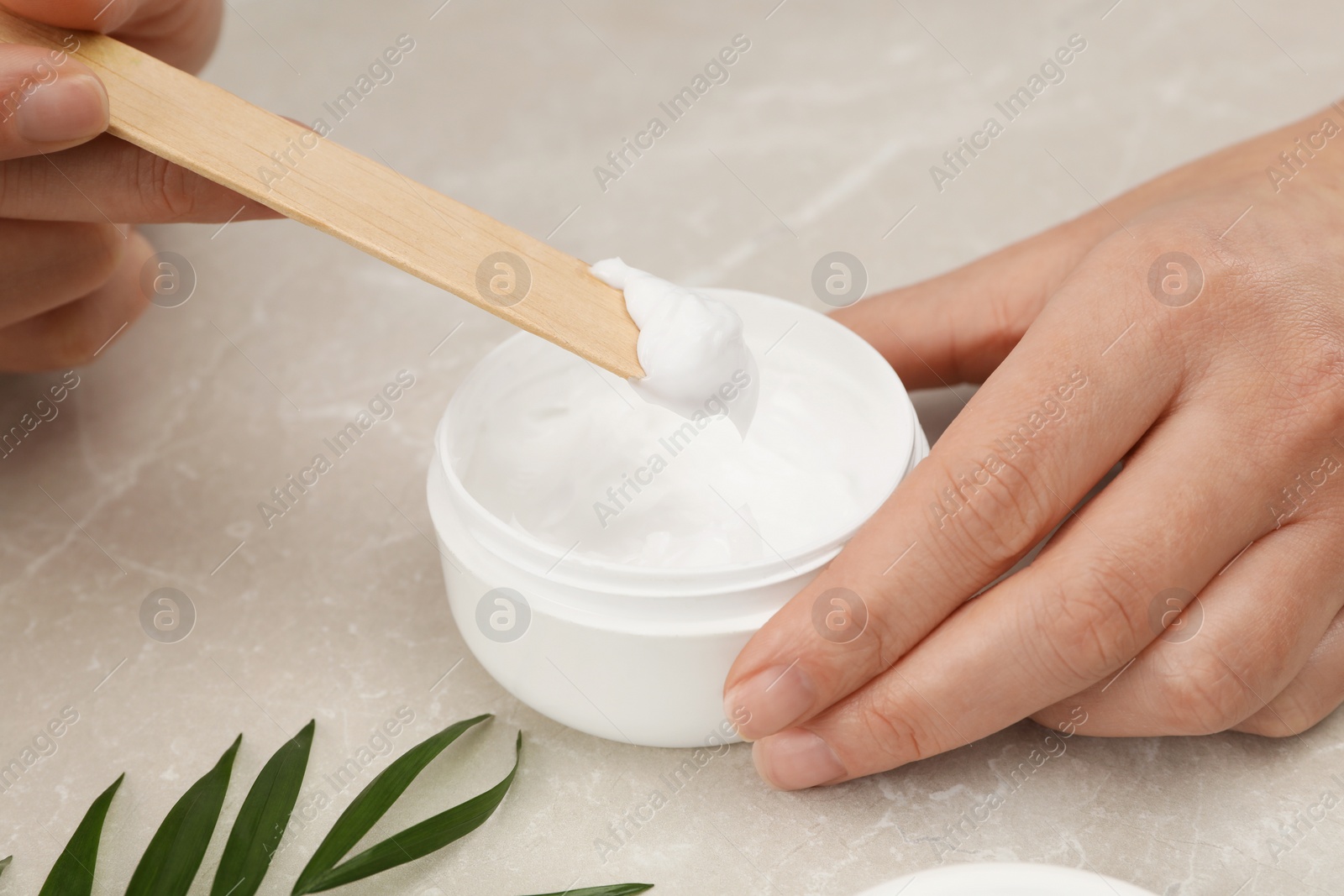 Photo of Dermatologist developing cosmetic product at light marble table, closeup