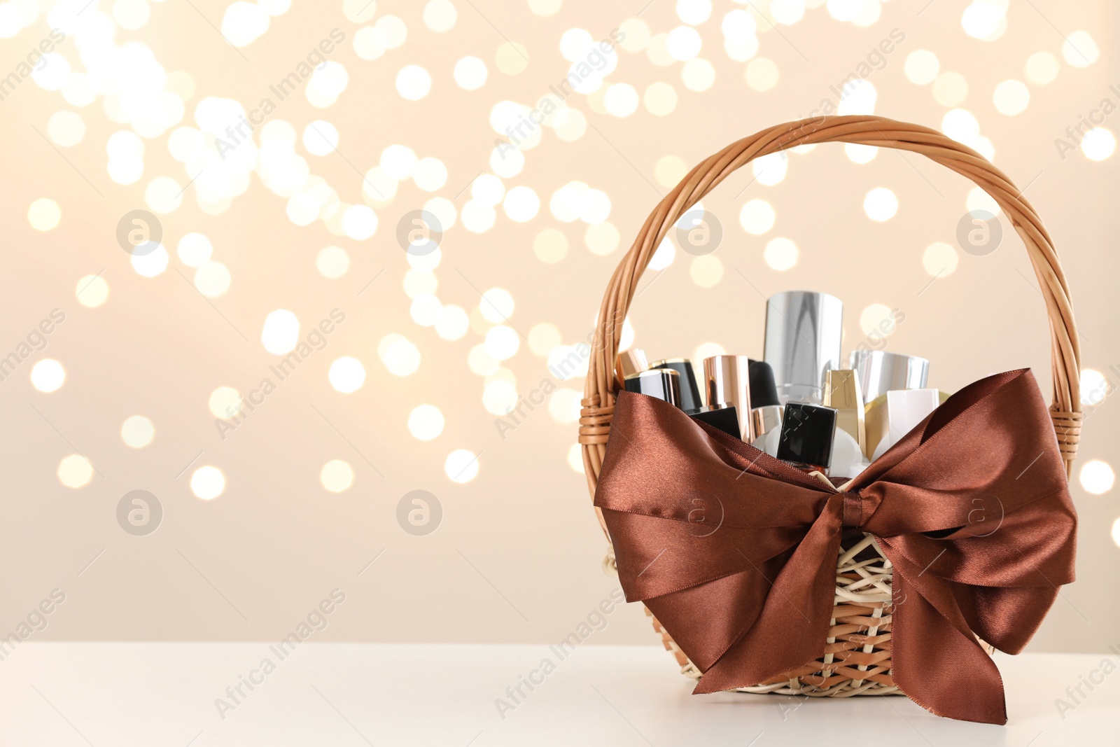 Photo of Wicker basket with cosmetics as present against blurred festive lights. Space for text