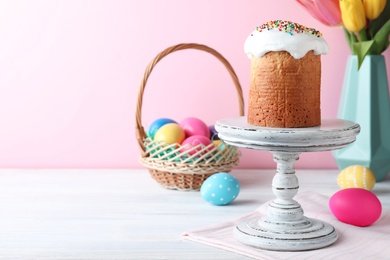 Photo of Easter cake, colorful eggs and tulips on white wooden table, space for text