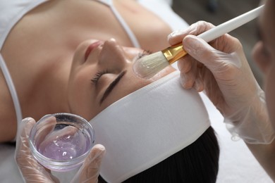 Photo of Young woman during face peeling procedure in salon