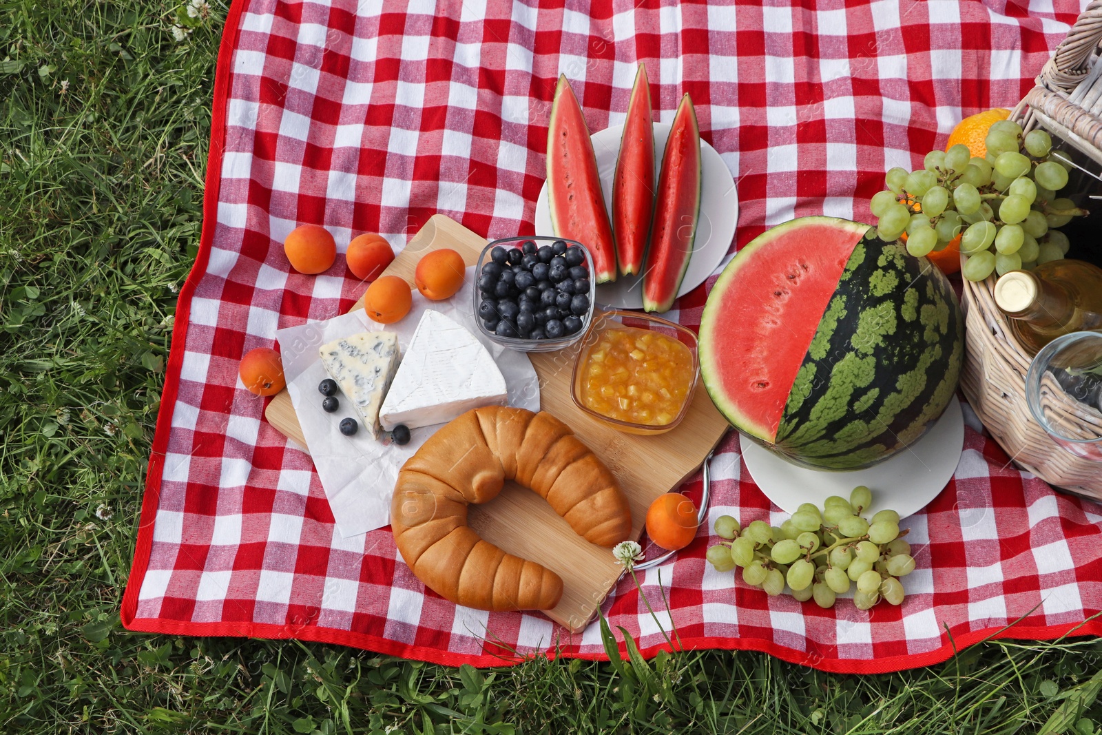 Photo of Picnic blanket with delicious food and wine outdoors on summer day