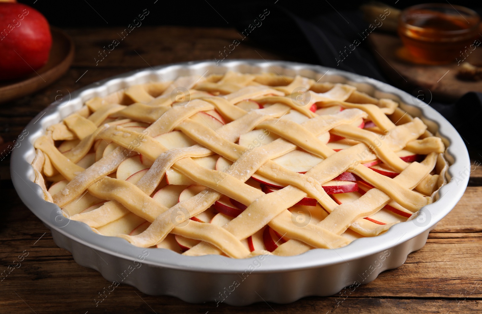 Photo of Raw traditional English apple pie in baking dish on wooden table, closeup