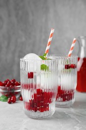 Photo of Delicious cocktails with cranberries, mint and ice balls on grey table