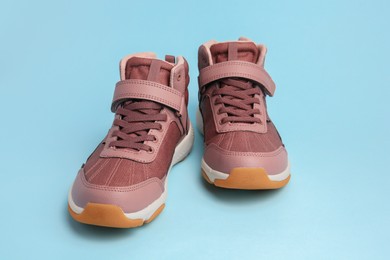 Photo of Pair of stylish kid's sneakers on light blue background