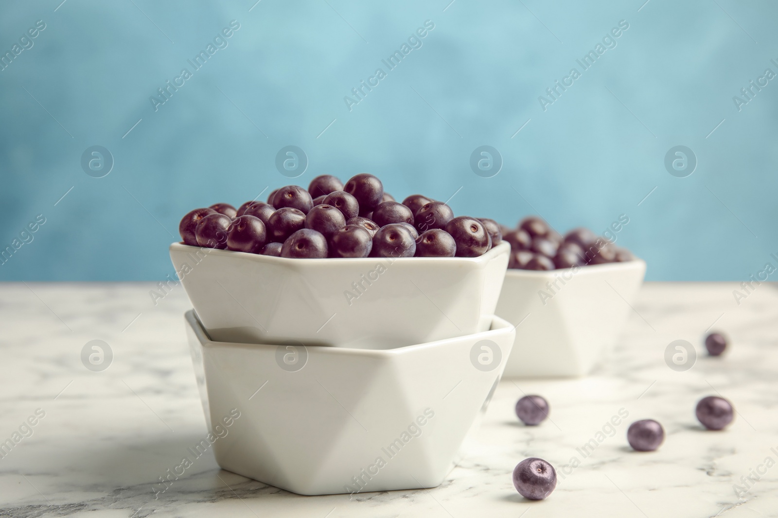 Photo of Bowls with fresh acai berries on marble table