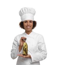 Photo of Happy female chef in uniform holding bottle of cooking oil on white background