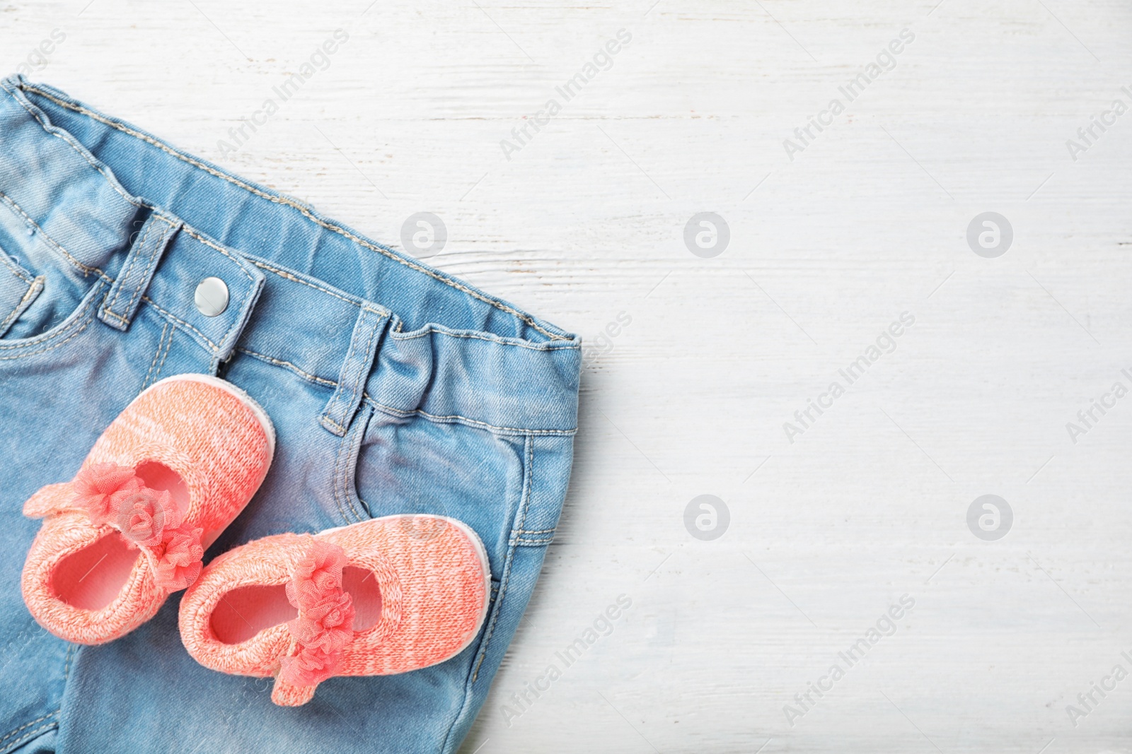 Photo of Pair of cute baby sandals and clothes on table, top view