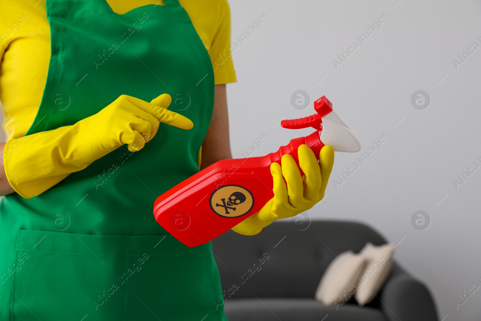 Photo of Woman pointing at bottle of toxic household chemical with warning sign, closeup