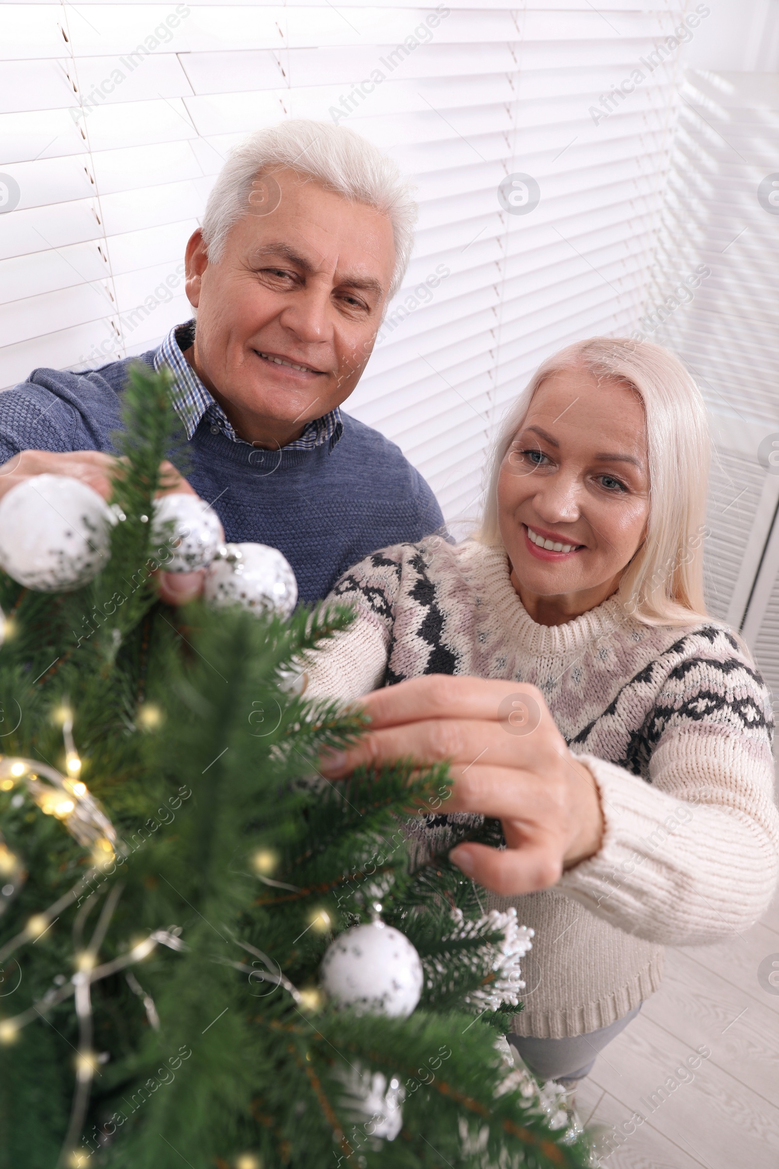 Photo of Happy mature couple decorating Christmas tree at home, above view