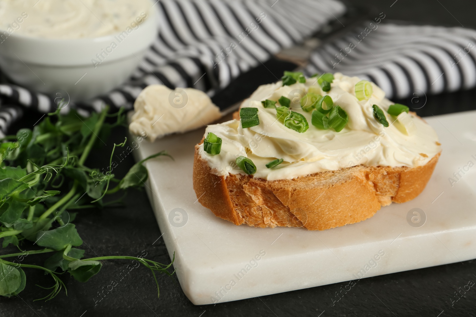 Photo of Delicious sandwich with cream cheese and microgreens on black table, closeup