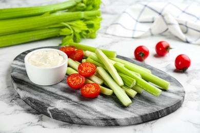 Photo of Celery sticks and tomatoes with dip sauce on white marble table