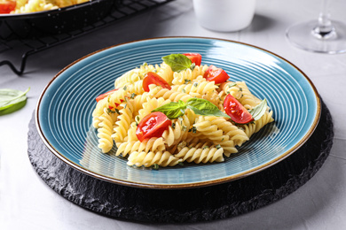 Photo of Delicious pasta with tomatoes and basil served on grey table